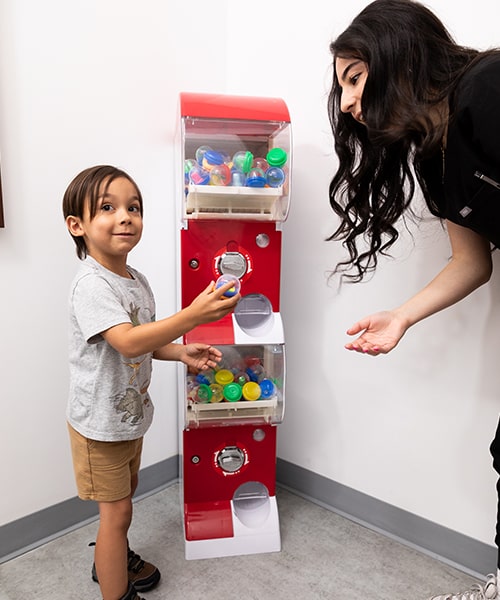 A child and one of our Northtown Kids Dental & Orthodontics assistants in a toy machine