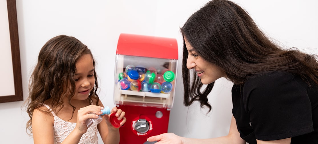 A girl and one of our assistants using a toy machine at the Northtown Kids Dental & Orthodontics office